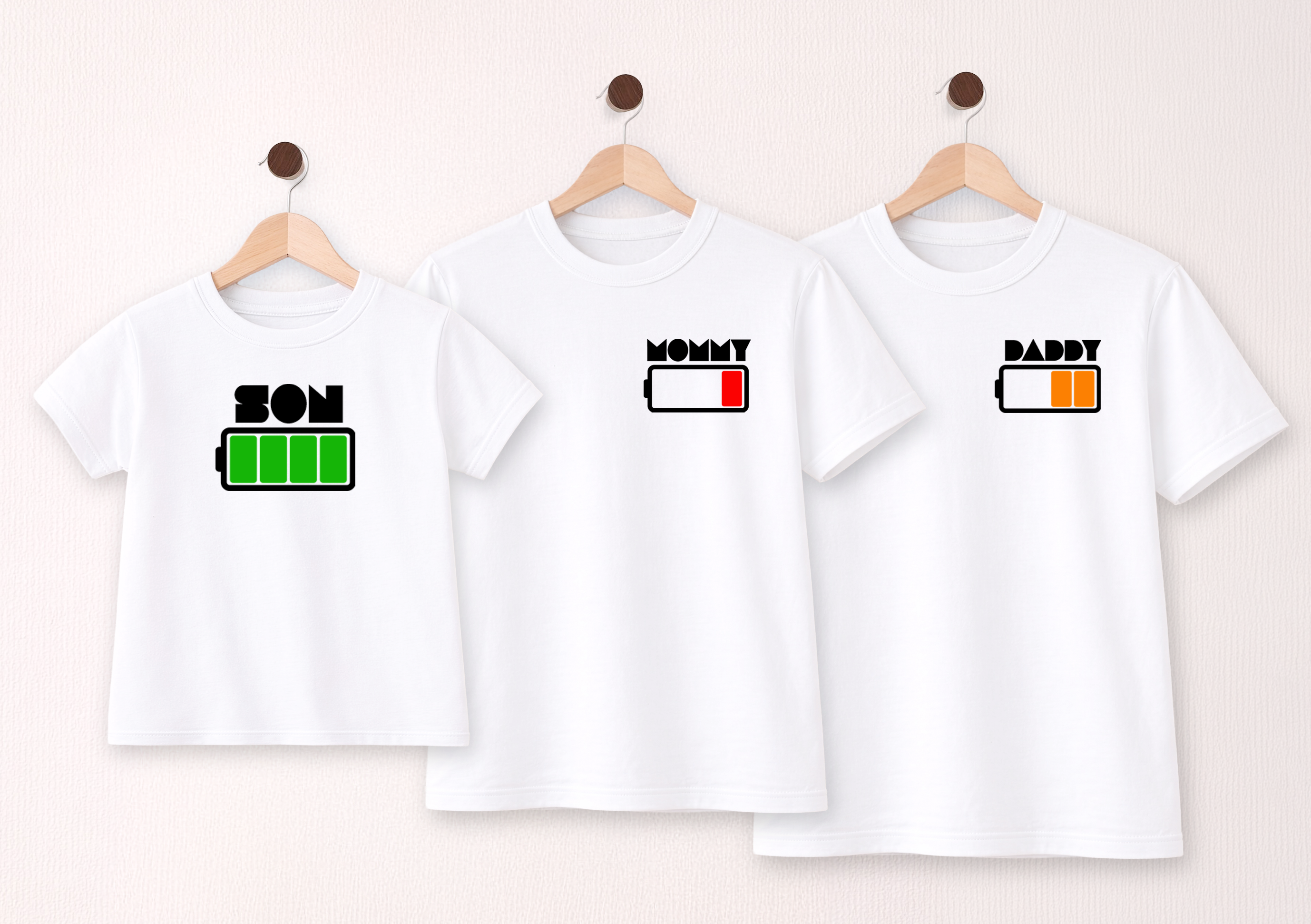 Three white t-shirts with 'Mom', 'Dad', and 'Son' text and battery icons on a beige background.